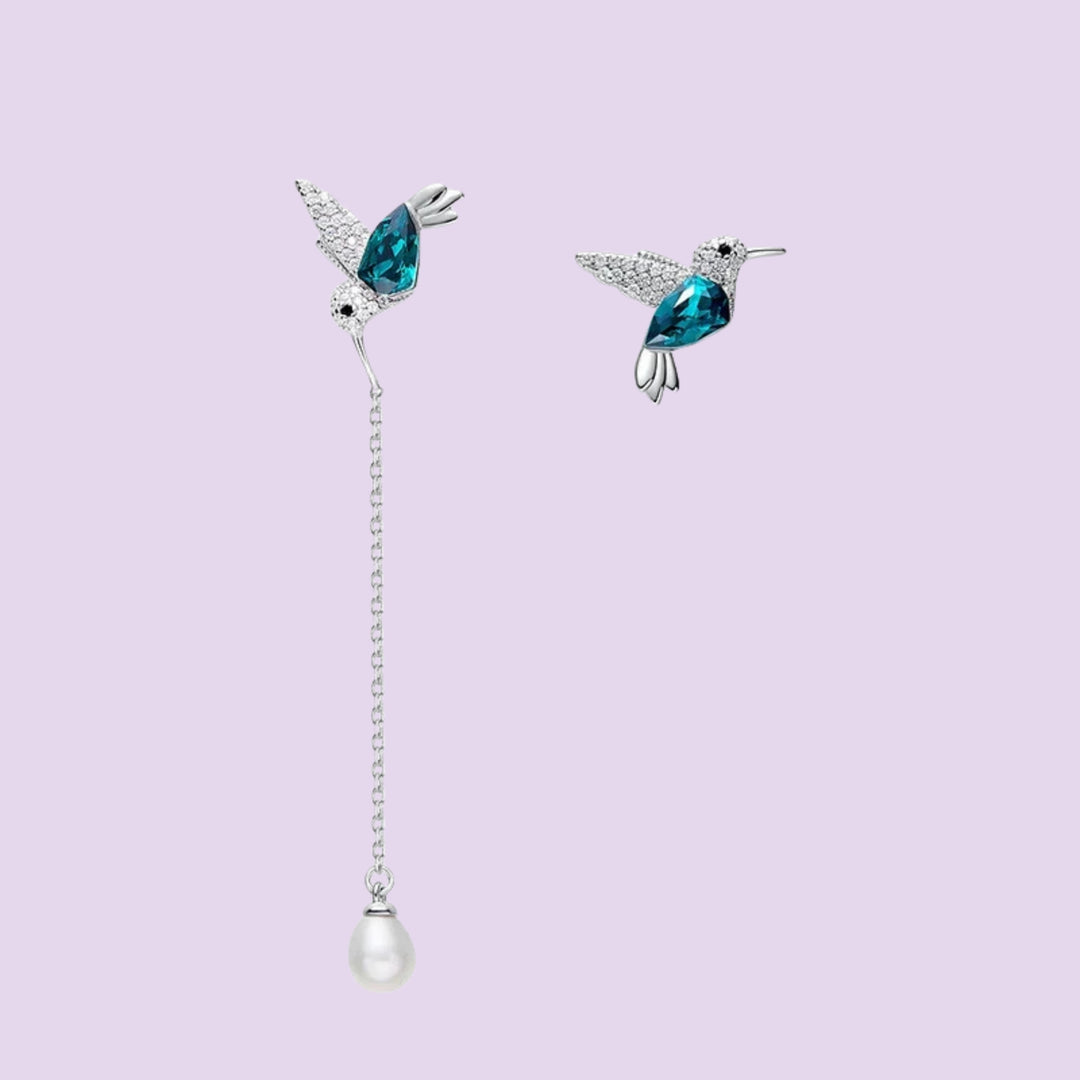 Hummingbird asymmetrical earrings close-up showing blue hummingbird designs and pearl drop detail