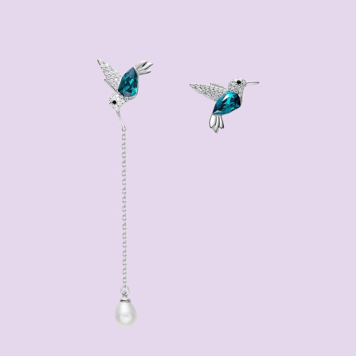 Hummingbird asymmetrical earrings close-up showing blue hummingbird designs and pearl drop detail